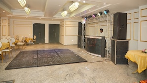 A spacious room with a stage, seating area, and a large screen. - Hotel Golden Valley (Faridabad)