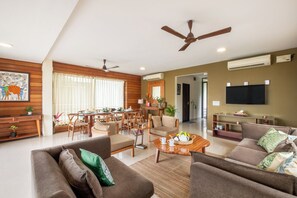 A modern living room with a sofa, coffee table, and dining area. - Staymaster Edge Water- Sea View 4BR (Nerul)