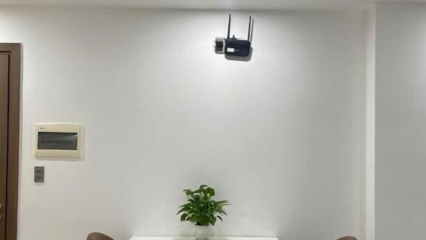 A modern dining area with a white table, brown chairs, a potted plant, and a ceiling-mounted device. - Sophia Center Apartment - The Duke Home (Rach Gia)