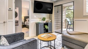 Un salon équipé d’un téléviseur à écran plat, d’un canapé, d’une table basse et d’une porte-fenêtre coulissante donnant sur un espace extérieur.