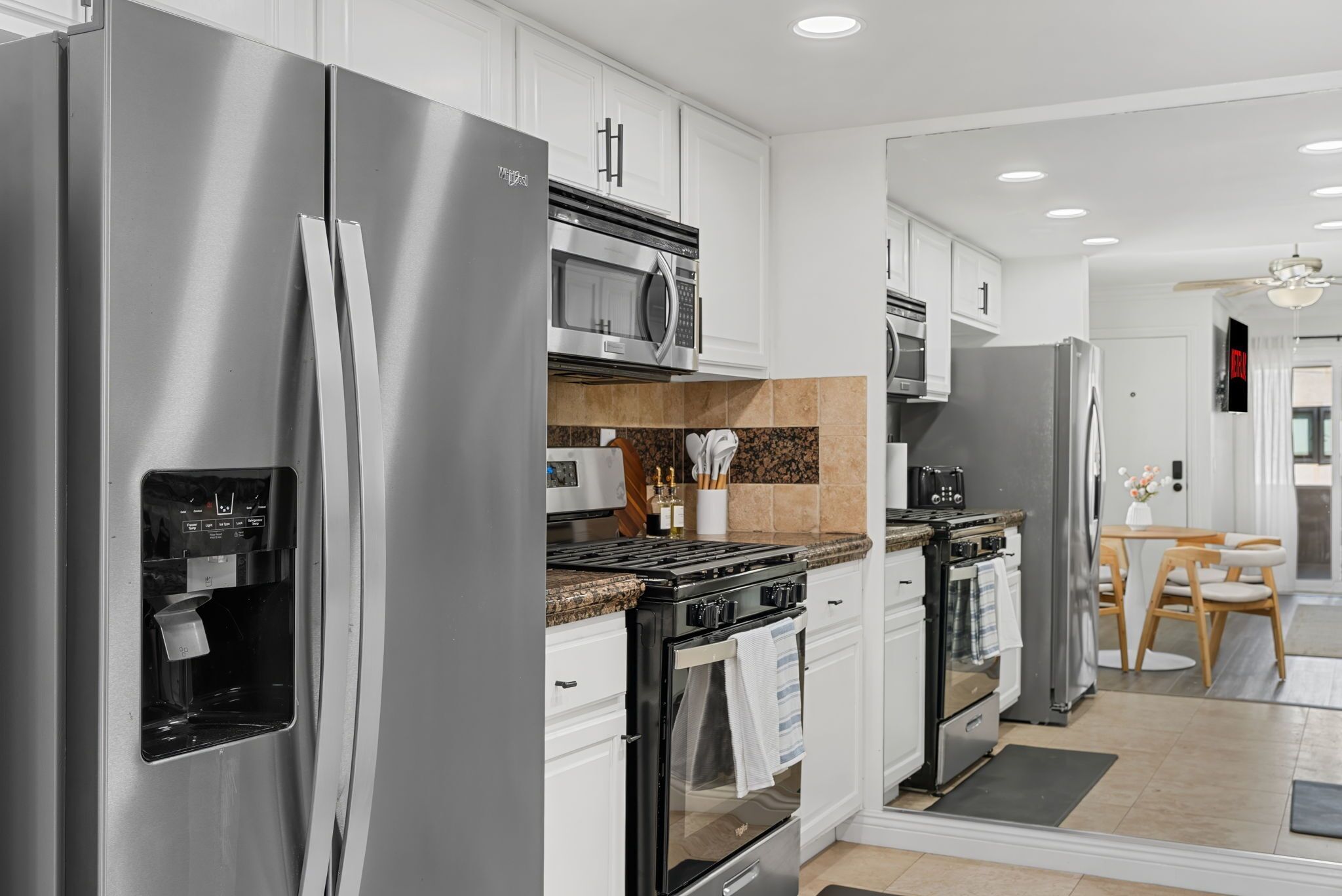 A modern kitchen with stainless steel appliances, white cabinetry, and a built-in stove.