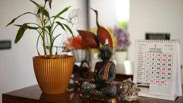 Una estatua de Buda, un calendario y una planta en maceta sobre una superficie de madera.