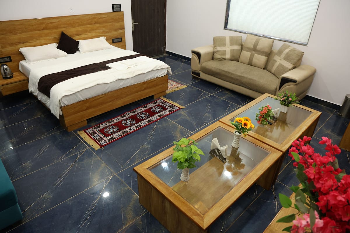 A bedroom with a bed, a sofa, a coffee table, and a nightstand.