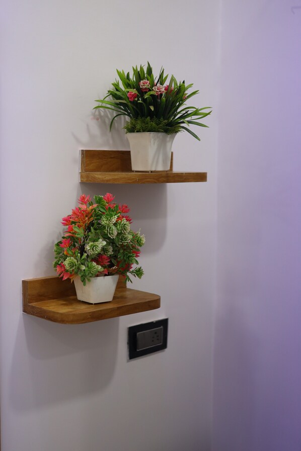 Two wooden shelves with potted plants against a wall. - The Sunflower Resort (Bharatpur)