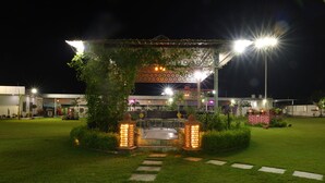 Ein Pavillon mit Fliesenboden, umgeben von einem gepflegten Rasen und einem Backsteinbau.