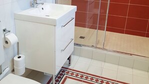 A bathroom with a white sink, toilet, and shower with red tiles. - Bed and breakfast La Villa Stella in Arcachon with swimming pool (La Teste-de-Buch)