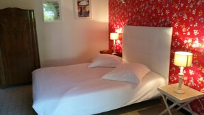 A bed with white bedding, a wooden wardrobe, a nightstand with a lamp, and a floral wallpaper. - Bed and breakfast La Villa Stella in Arcachon with swimming pool (La Teste-de-Buch)