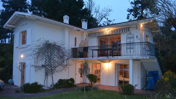 A two-story house with a balcony, a garage, and a well-maintained lawn. - Bed and breakfast La Villa Stella in Arcachon with swimming pool (La Teste-de-Buch)