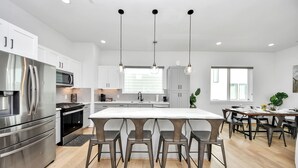 Uma cozinha moderna com eletrodomésticos de aço inoxidável, uma ilha central com banquetas e iluminação pendente.