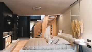A modern interior with a bed, a round table, a staircase, and a large mirror.