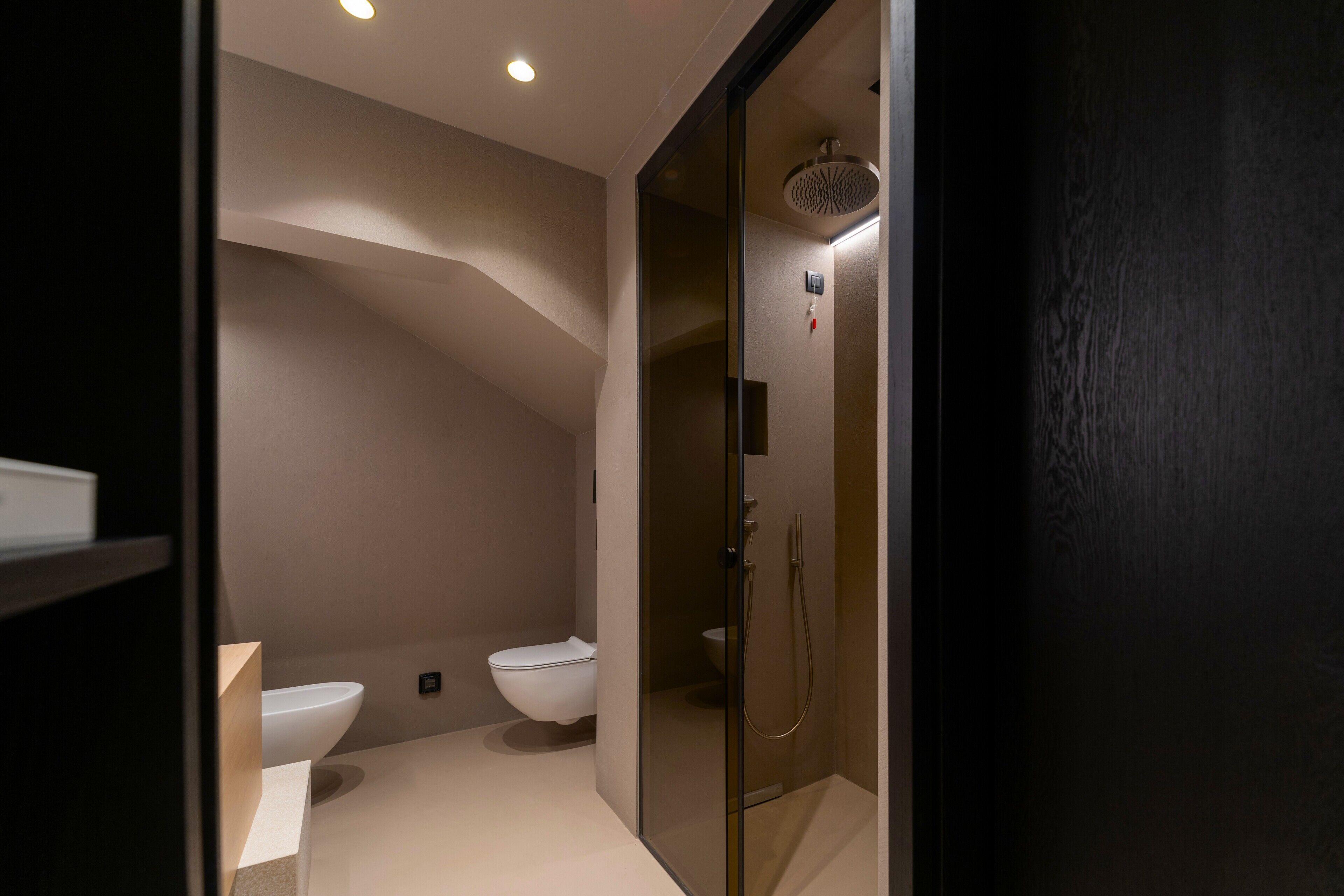 Een moderne badkamer met een douche met glazen wand, een wit toilet en een wastafel.