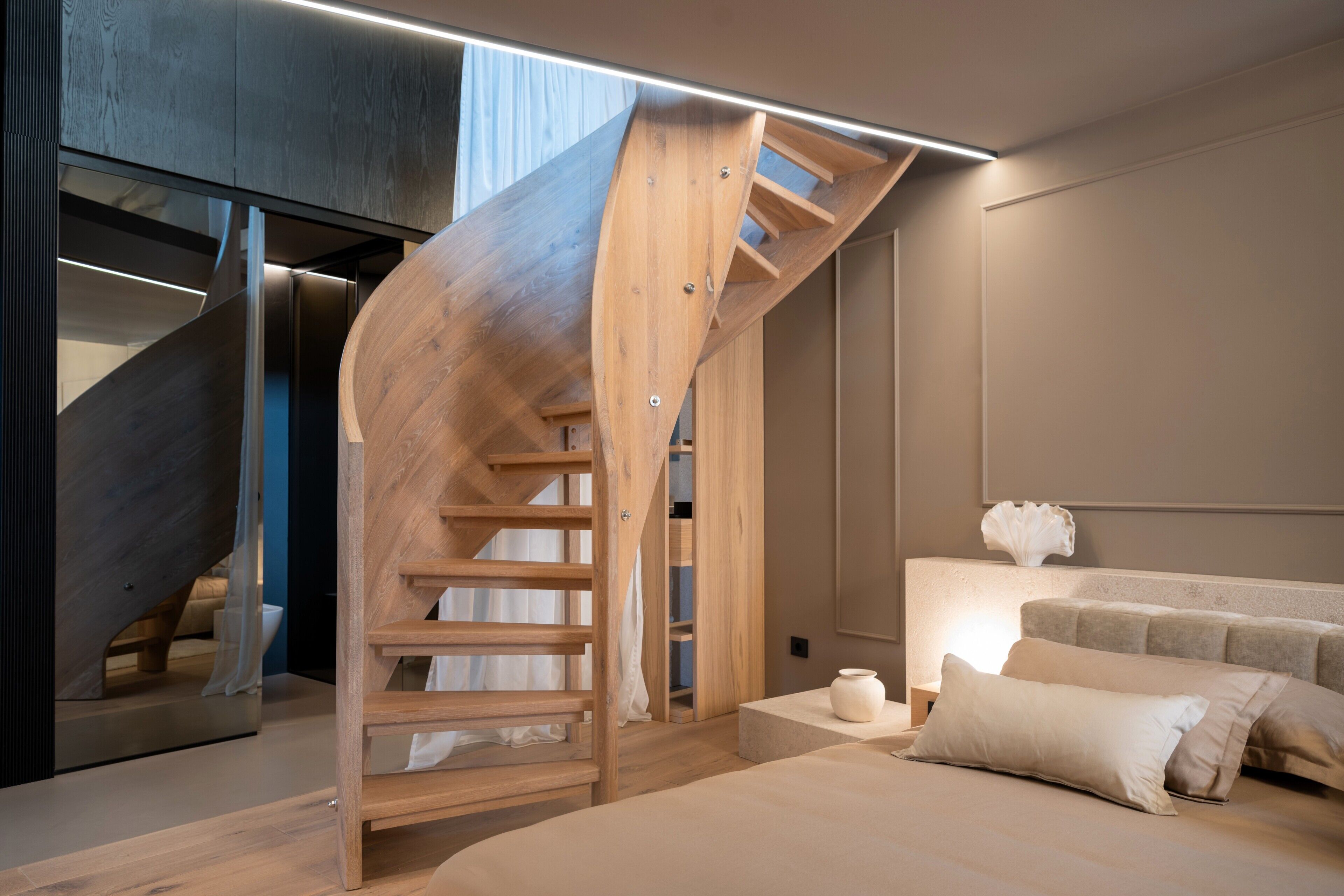 Un dormitorio moderno con una escalera de madera, una cama con almohadas y una mesita de noche.