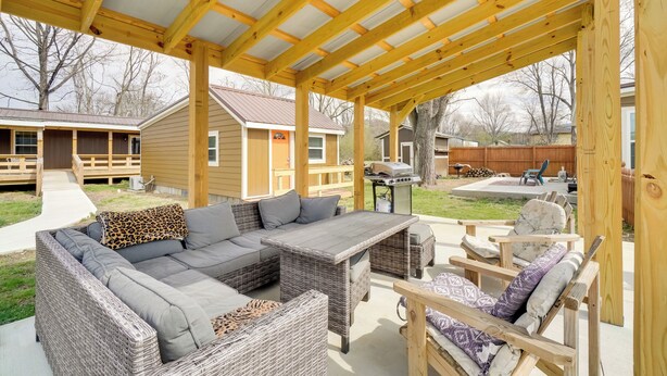 Un porche exterior cubierto con un sofá modular, mobiliario de mimbre y una zona de barbacoa.