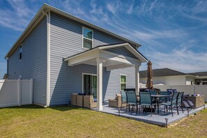 A house with a covered patio, outdoor furniture, and a white fence.