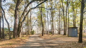 A campground with a dirt path, trees, and small cabins.