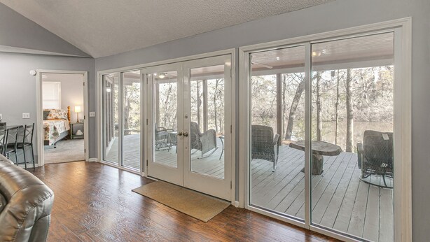 A spacious room with a large sliding glass door leading to an outdoor deck with outdoor furniture.