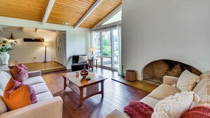 Un salón amplio con techo de madera, chimenea y un ventanal grande.