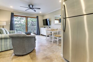 A modern kitchen with a stainless steel refrigerator, a dining area with white chairs, a gray sofa, and a ceiling fan. - Steps to Shore & Restaurants: Coligny Beach Gem! (Hilton Head Island)