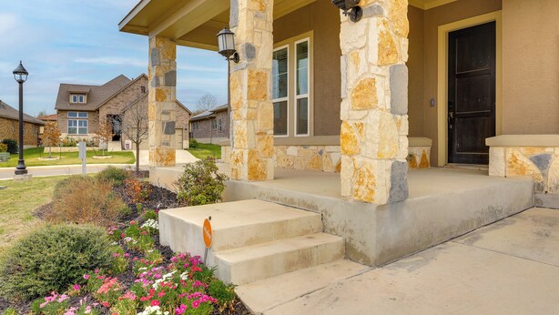 A residential house with a stone porch, a front door, and a small garden with flowers. - 2 Mi to TPC San Antonio: Group Getaway w/ Theater! (San Antonio)