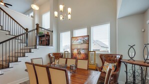 A dining area with a wooden table and chairs, a chandelier, and a staircase with a railing. - 2 Mi to TPC San Antonio: Group Getaway w/ Theater! (San Antonio)