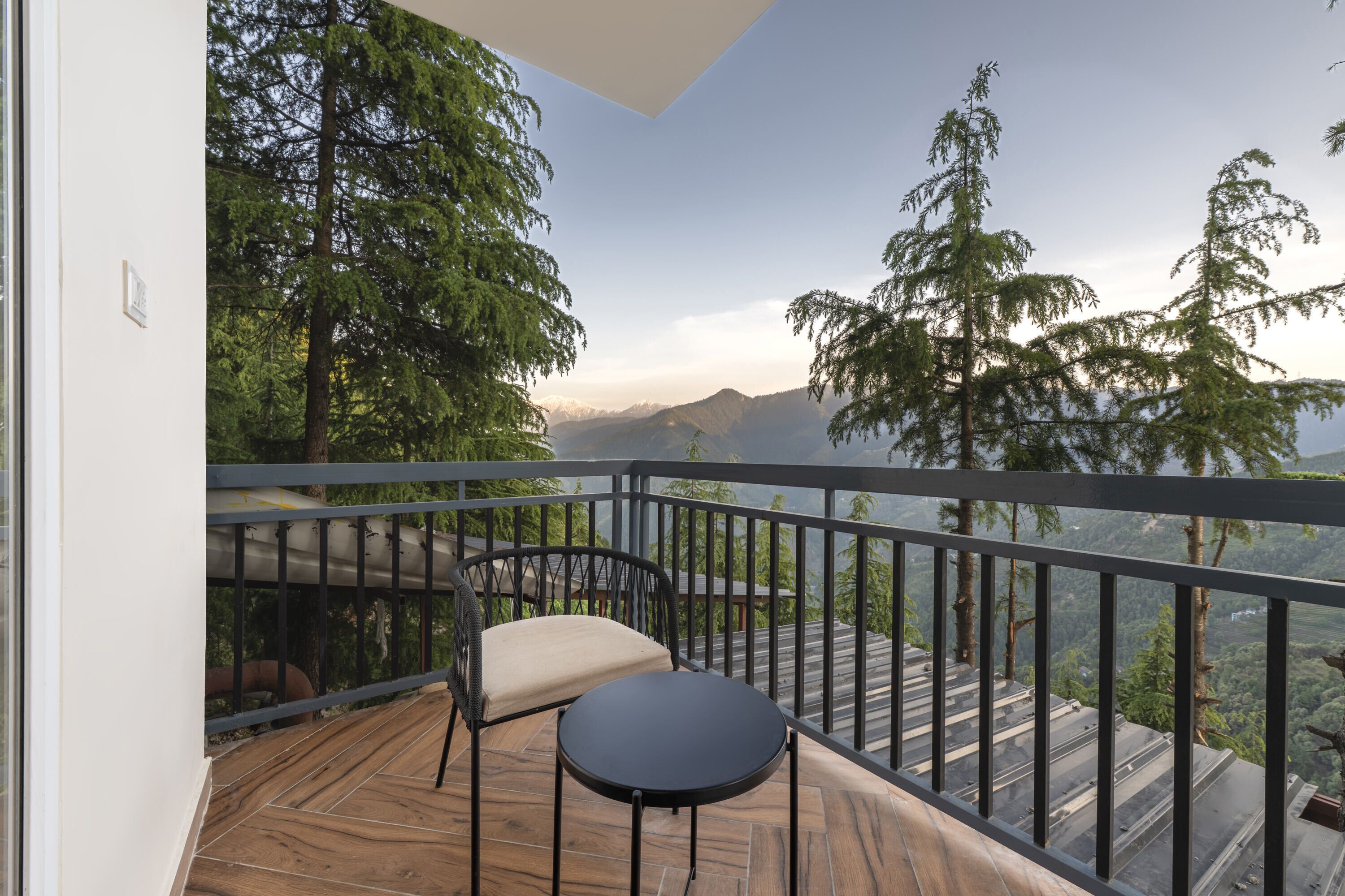 A balcony with a table and chair, overlooking a mountainous landscape.