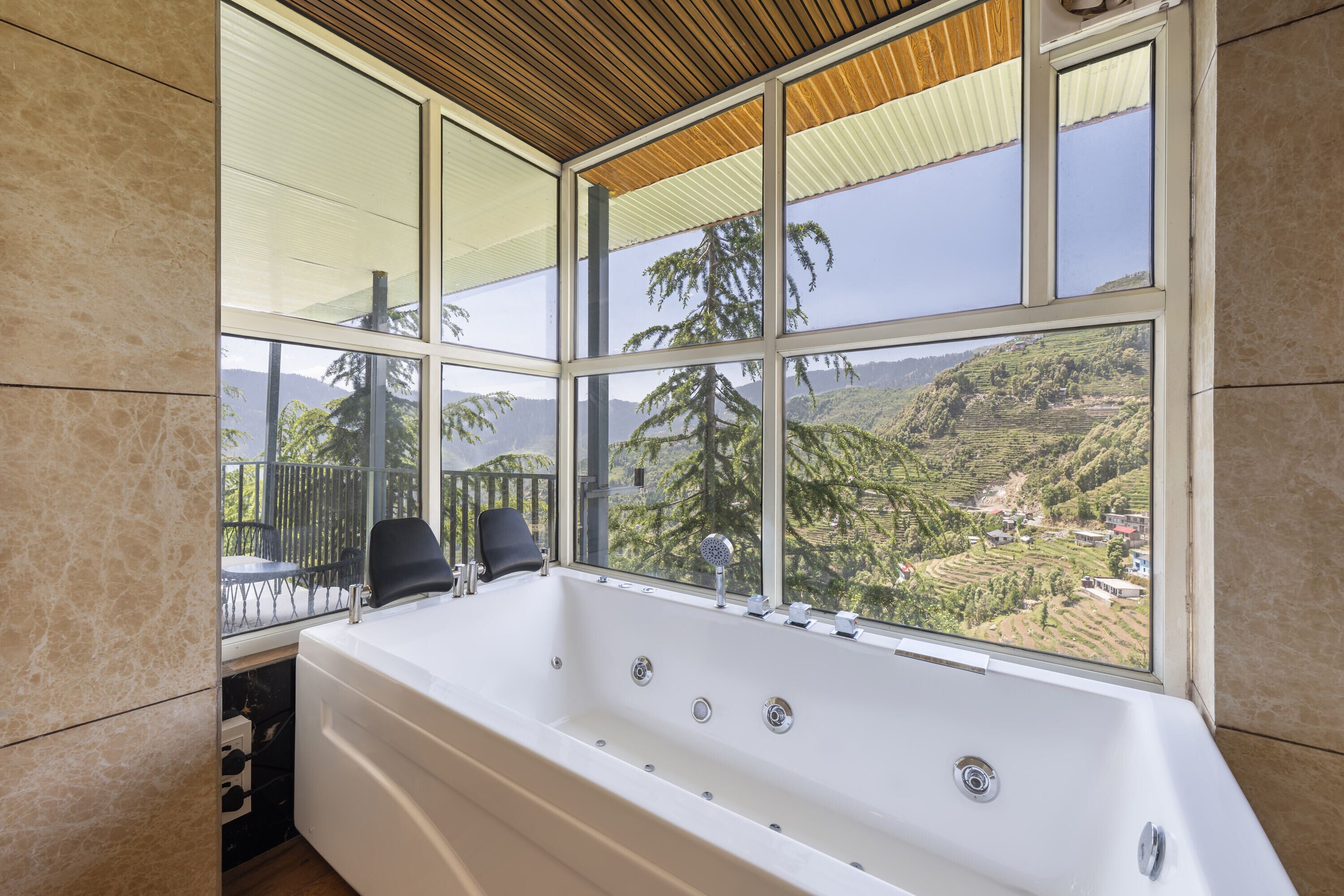 Un baño con una bañera grande, vistas a un paisaje montañoso a través de un ventanal amplio y un techo de madera.