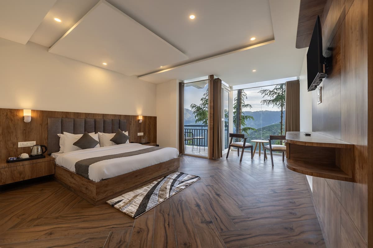Un dormitorio moderno con una cama grande, cabecera de madera, mesitas de noche, televisor de pantalla plana y un balcón con vistas.