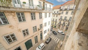 Una calle estrecha flanqueada por edificios, un coche blanco estacionado y un paso de peatones.