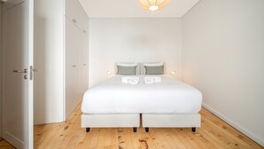 Un dormitorio con cama, lámparas de noche, una puerta y una lámpara en el techo.