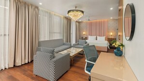 Ett hotellrum med en soffgrupp, en säng, ett skrivbord och en kristallkrona.