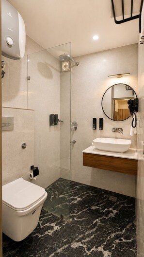 A modern bathroom with a glass-enclosed shower, a toilet, a sink with a wooden vanity, and a round mirror. - Country Inn Rishikesh (Rishikesh)