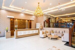 A modern lobby with a reception desk, sofas, a chandelier, and a staircase. - Country Inn Rishikesh (Rishikesh)