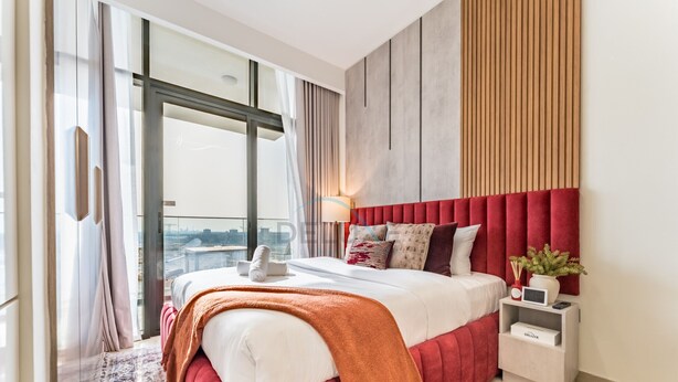 Une chambre moderne avec un grand lit, une table de chevet, une lampe et une vue sur la ville grâce à une grande fenêtre.