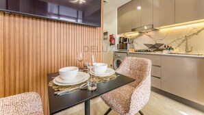 Une cuisine moderne équipée d’un four à micro-ondes, d’une cuisinière et d’un évier. On y trouve une table à manger mise avec des assiettes, des verres et des couverts.