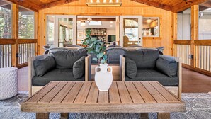 Eine Holzterrasse mit Tisch, zwei Sofas, einer weißen Vase und einer Holzbeschichtung an der Decke.