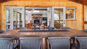 Ein Holzinterieur mit Essbereich, Korbstühle, Kamin und großem Fenster.