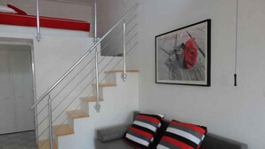 A modern living room with a grey sofa, striped pillows, a staircase with metal railings, and a framed artwork on the wall. - Studio with shared pool (Stanići)