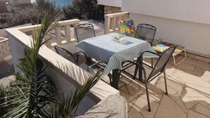 A patio with a table and chairs, overlooking a body of water and hills. - Studio with shared pool (Stanići)