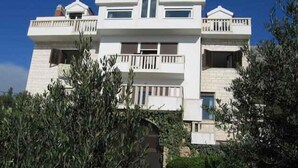 A multi-story building with balconies, a central entrance, and a symmetrical facade. - Studio with shared pool (Stanići)