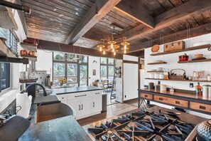 Een moderne keuken met een centraal eiland, houten balken en een hanglamp.
