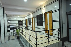 Un hall d’hôtel moderne avec des murs en marbre, un comptoir d’accueil, un escalier et un balcon.