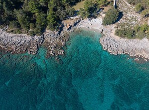 An aerial view of a coastal area with rocky terrain and clear turquoise waters. - Holiday Apartment Exclusive Flat Marija (Krk)