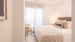 A bedroom with a bed, a chair, a nightstand, and a window with curtains. - Sunny 2-Bedroom Apartment | Pool & Terrace | Estepona (Estepona)