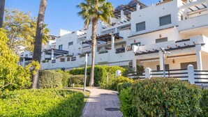 A multi-story hotel with a central courtyard, surrounded by lush greenery and palm trees. - Sunny 2-Bedroom Apartment | Pool & Terrace | Estepona (Estepona)