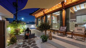 Un pati amb mobiliari exterior, una llar de foc i una estructura de pergola.