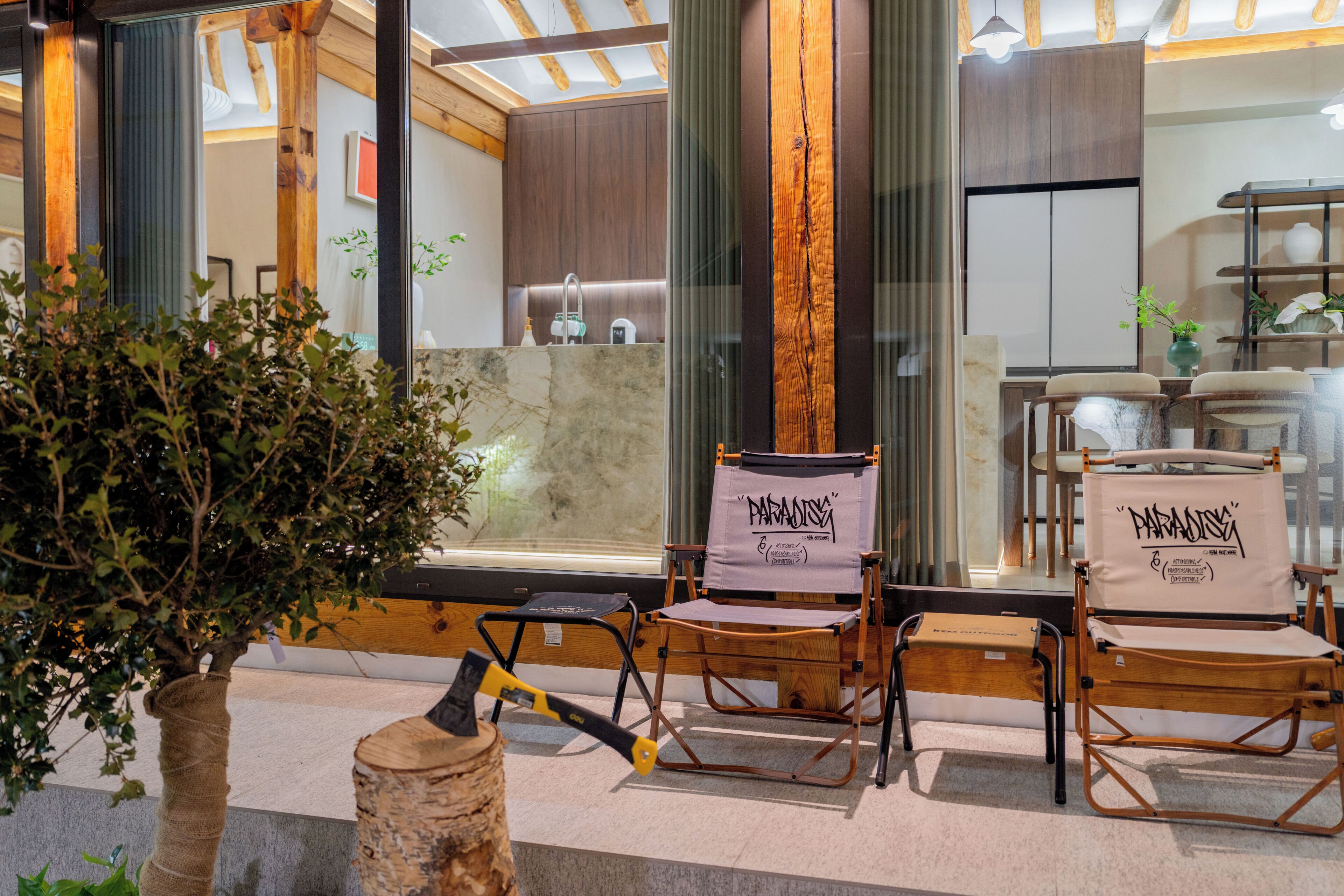 A modern interior with wooden beams, a stone wall, and two folding chairs with 'PARADISE' banners.