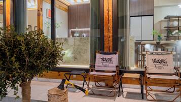 A modern interior with wooden beams, a stone wall, and two folding chairs with 'PARADISE' banners.