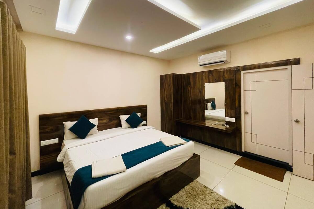 A bedroom with a bed, a wardrobe, a mirror, and a ceiling light fixture.