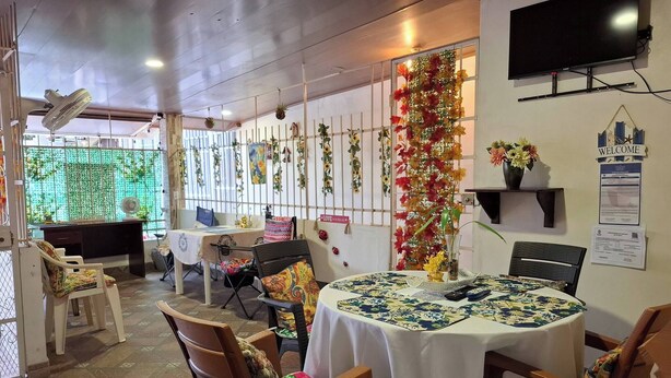 A dining area with a round table, chairs, a TV, and decorative plants. - Apartamento Lilia Airport 1 (Panamá)