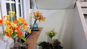 A narrow hallway with a wooden shelf holding a vase of flowers and a small table with additional flowers. - Apartamento Lilia Airport 1 (Panamá)